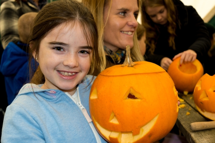 A young girl holding up her carved pumpkin at WWT Martin Mere